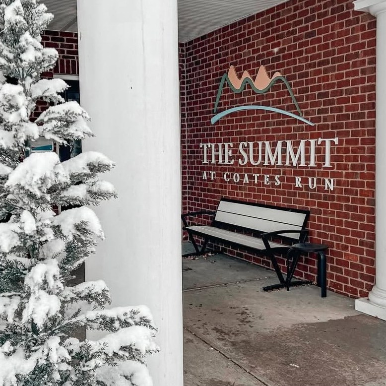 The Summit front sign with a snowy tree in the foreground